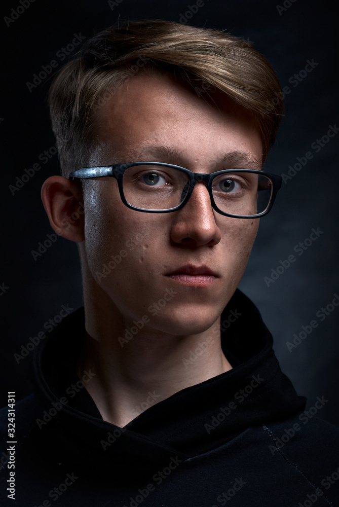 Smart teenager with short hair and glasses an black background. Strong and handsome face. Smart teenager with short hair and glasses an black background. Strong and handsome face.