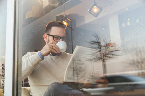 Man reading newspapers and drinking coffee