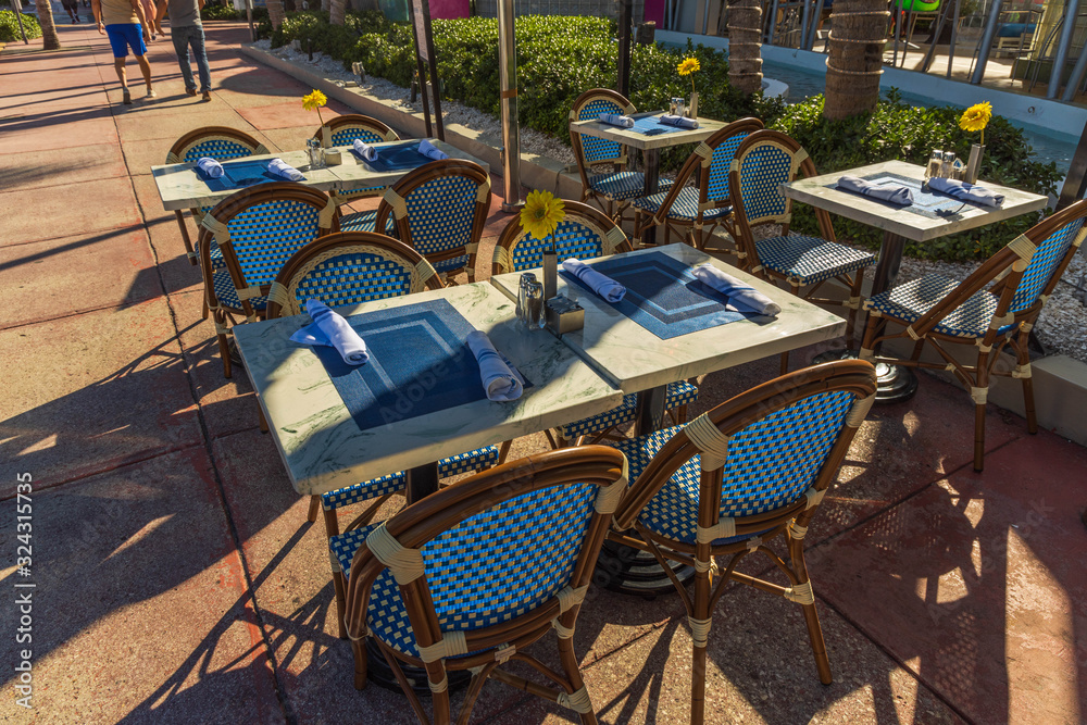 Beautiful view of outdoor cafe. Wooden chairs and tables covered with blue napkins. Food and drink concept.