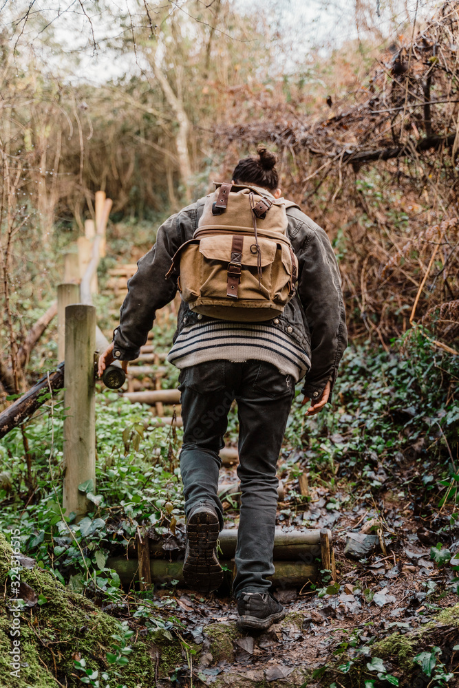 Young man with backpack, walking in nature, rear view Young man with backpack, walking in nature, rear view