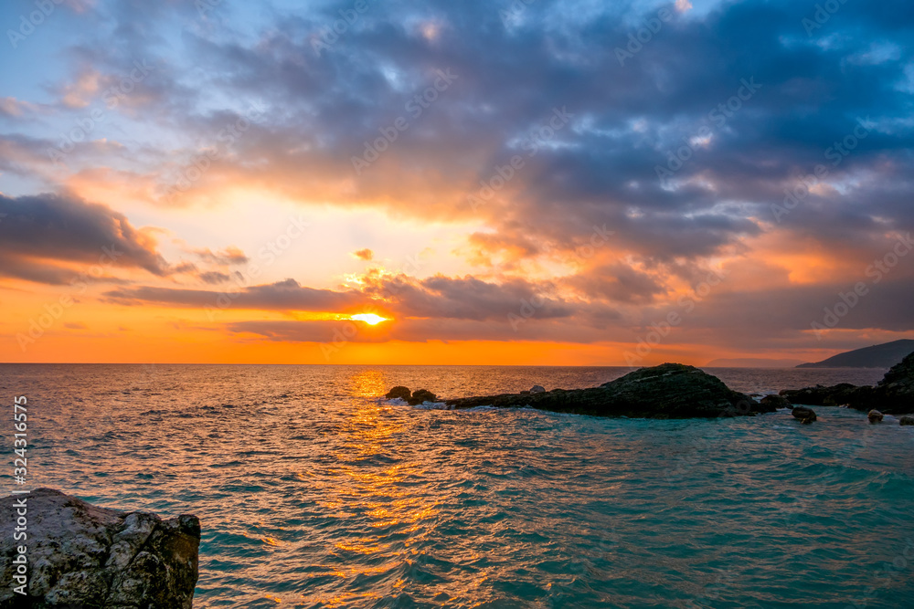 Naklejka premium Sea Dawn and Sun Rays on the Rocky Shore