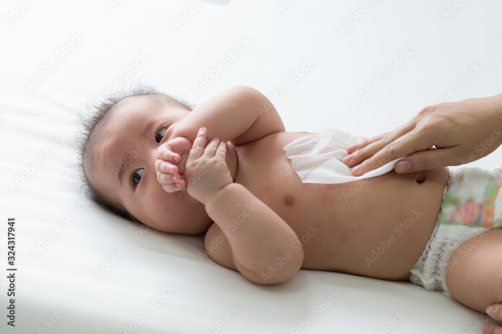 Obraz premium Mom cleaning up and wipe body baby by wet tissue when changing nappies or diaper and wiping the hands or face or leg, Personal hygiene for mother and Toddler kid with wet wipes paper concept