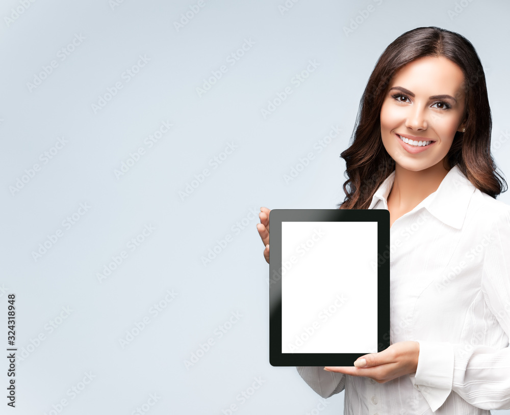 Business woman showing blank tablet pc, on grey Business woman showing blank tablet pc, on grey