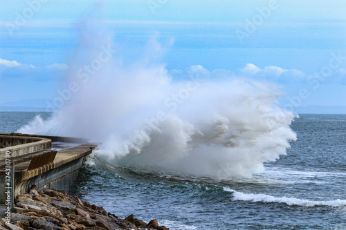 Big ocean wave hitting pier. Storm waves