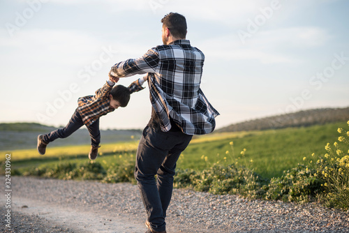 Bild auf Leinwand Spinning father grabbing his son with his arms