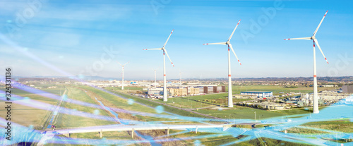 Centrale eolica in pianura con turbine e industrie come sfondo. Fonte di energia elettrica ecologica verde rinnovabile. Panoramica.