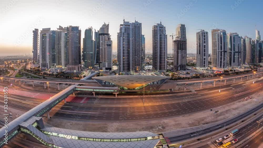 Aerial panoramic view to Sheikh Zayed road from Dubai Marina with JLT illuminated skyscrapers night to day transition timelapse, Dubai. Traffic, bridges and metro station. United Arab Emirates Aerial panoramic view to Sheikh Zayed road from Dubai Marina with JLT illuminated skyscrapers night to day transition timelapse, Dubai. Traffic, bridges and metro station. United Arab Emirates