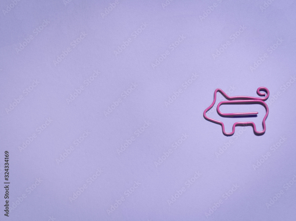 top view of pink piggy paper clip on purple background with copy space top view of pink piggy paper clip on purple background with copy space