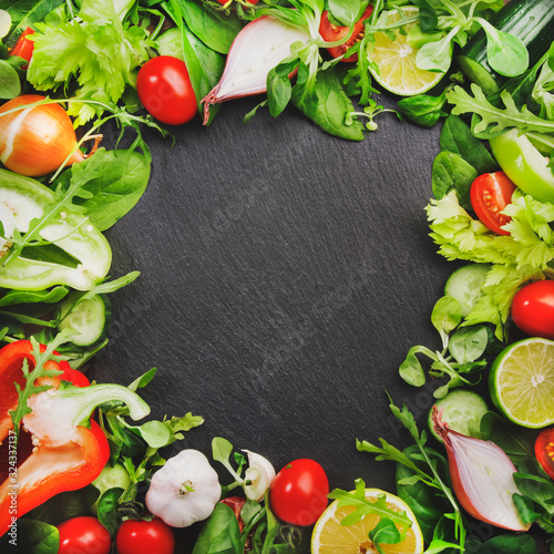 Healthy food background with various green herbs and vegetables. Ingredients for cooking salad. Vegetarian and vegan food concept. Top view  slate frame with copy space