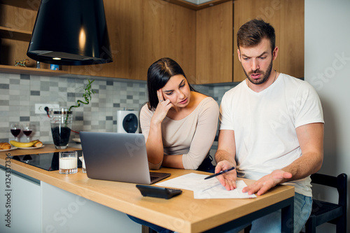 Worried couple looking at unpaid bills at home