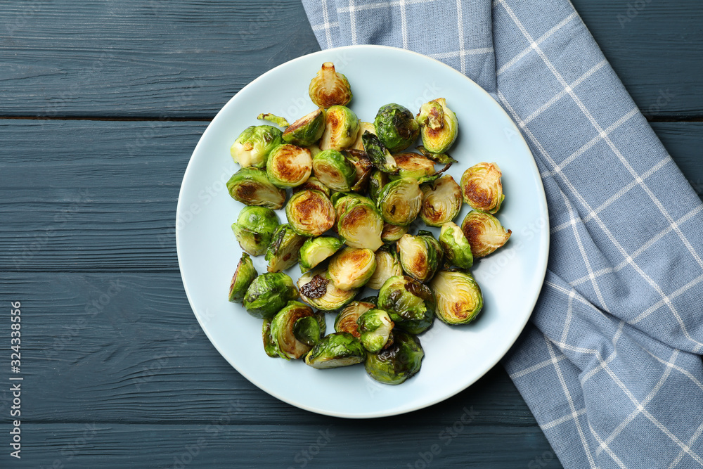 Plate with brussels sprout on wooden background, top view