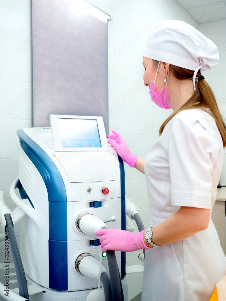 Equipment for the removal of superficial vessels by laser. Hardware treatment of facial redness. Portrait of cosmetologist using laser machine in beauty salon