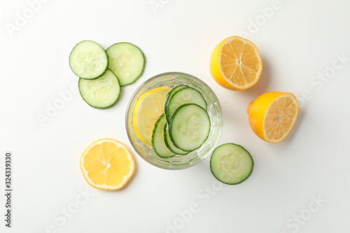 Glass with cucumber water, cucumber and lemon on white background, top view