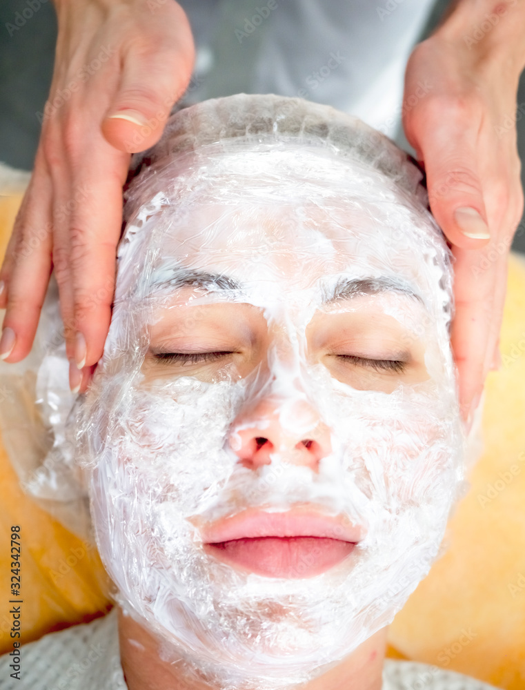 Girl beautician applies a to rejuvenate a mask on the face of an attractive girl in a spa salon. Beautiful woman during rejuvenation procedure. Face treatment at cosmetic clinic. Girl beautician applies a to rejuvenate a mask on the face of an attractive girl in a spa salon. Beautiful woman during rejuvenation procedure. Face treatment at cosmetic clinic.