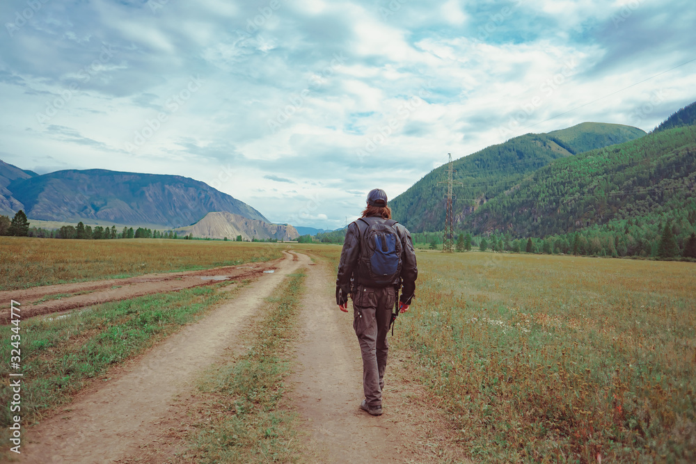 Naklejka premium guy with a backpack near the mountains