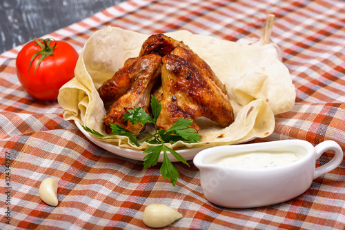 grilled chicken wings with fresh vegetables on lavas with sauce photo