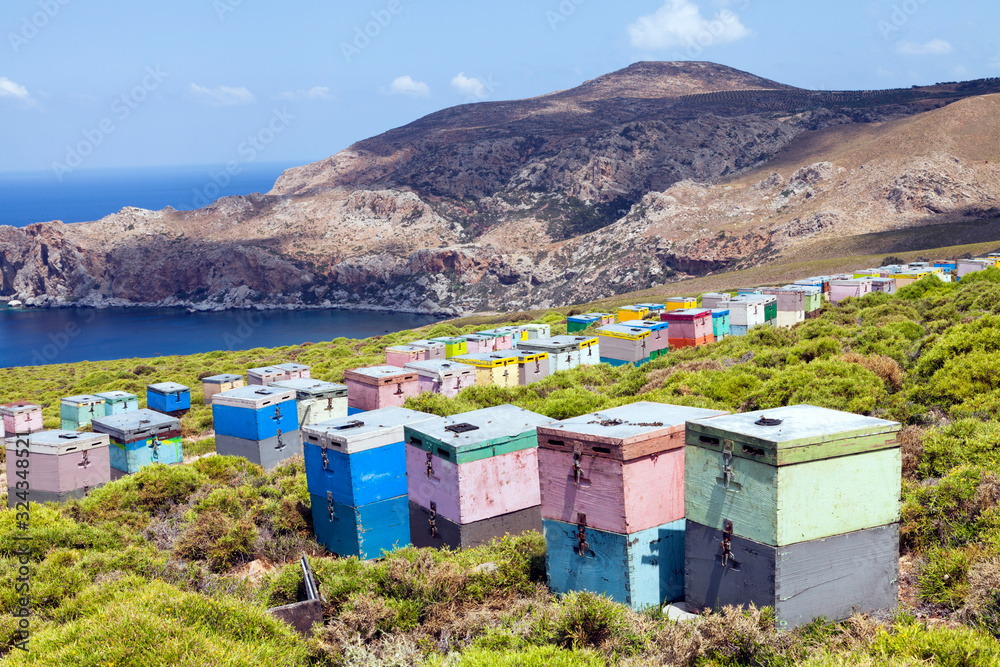 Colorful wooden beehive boxes on the Mediterranean sea cliff with rocky mountain in the background .