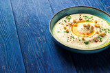 Chickpea hummus in a bowl on a dark blue wooden background