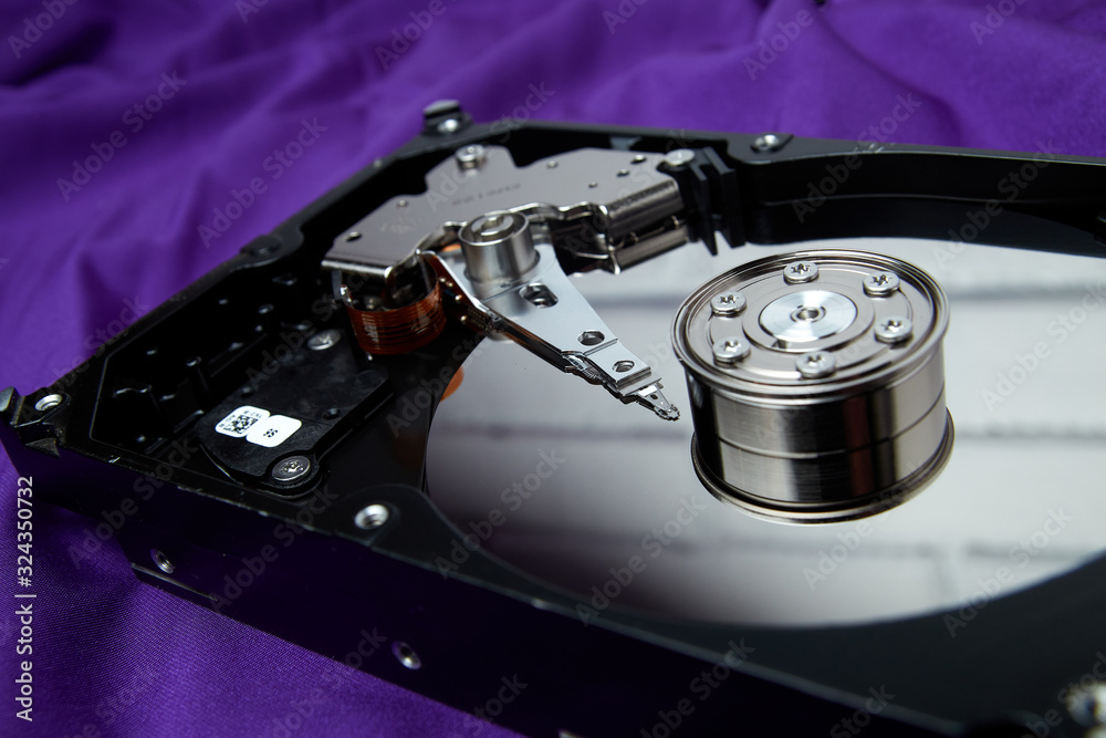 Opened hard drive from the computer hdd disk drive with mirror effects on violet background. Disassembled hard drive from the computer Opened hard drive from the computer hdd disk drive with mirror effects on violet background. Disassembled hard drive from the computer
