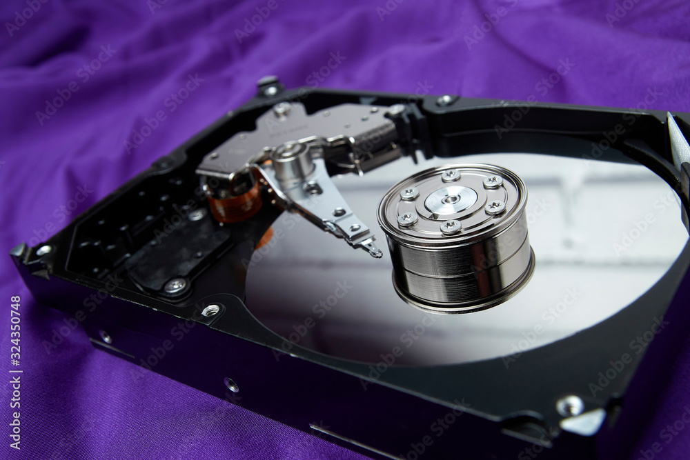 Opened hard drive from the computer hdd disk drive with mirror effects on violet background. Disassembled hard drive from the computer Opened hard drive from the computer hdd disk drive with mirror effects on violet background. Disassembled hard drive from the computer