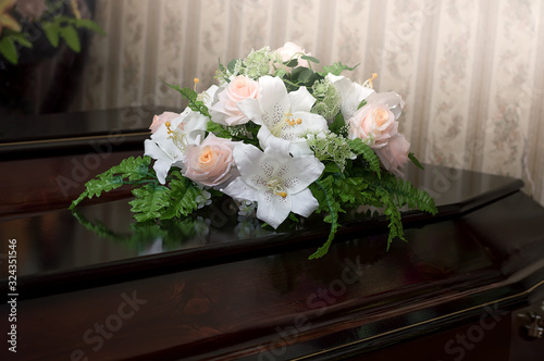 A wooden coffin of dark color is decorated with flowers. Funeral, burial. Death.