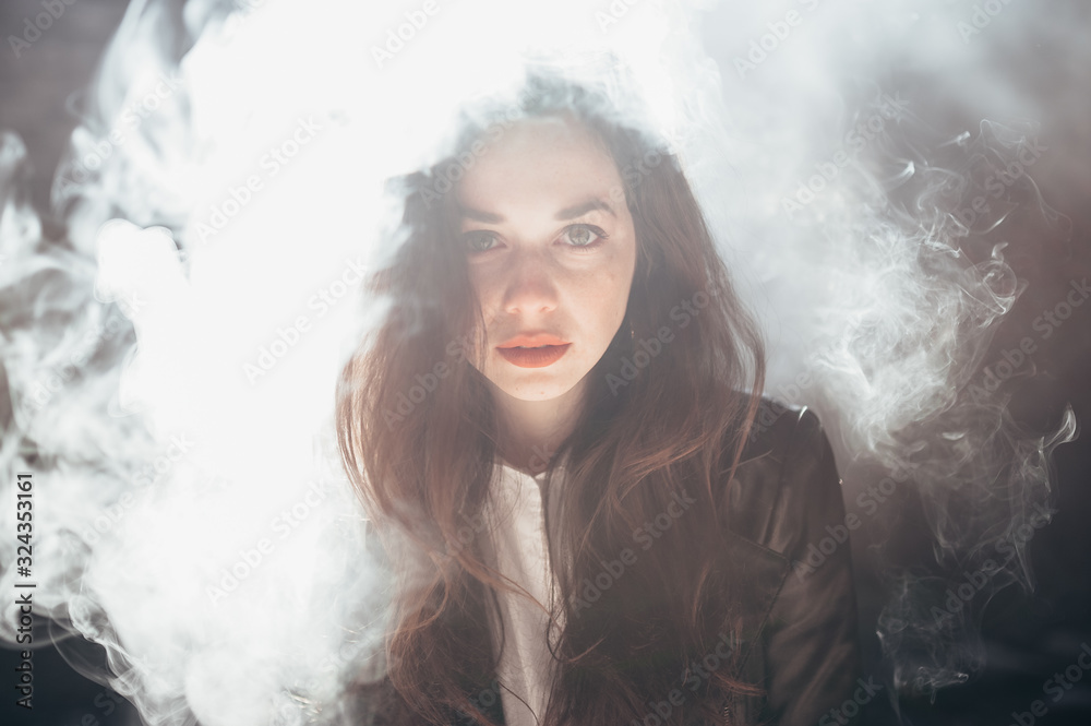 Brunette girl with red lipstick in the smoke.
