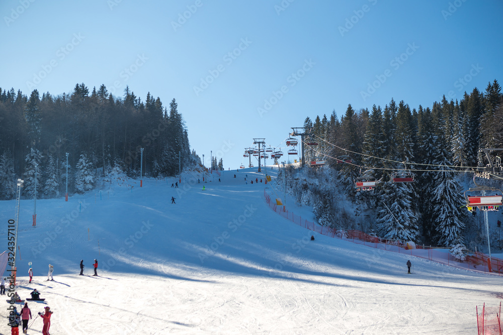 Beautiful sunny day on the mountain in winter. She looks down from the cable car to the ski slope where she has been hiding.