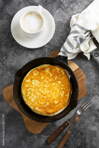 Omelette in frying pan and cup of coffee. Freshly cooked healthy omelette over dark background.