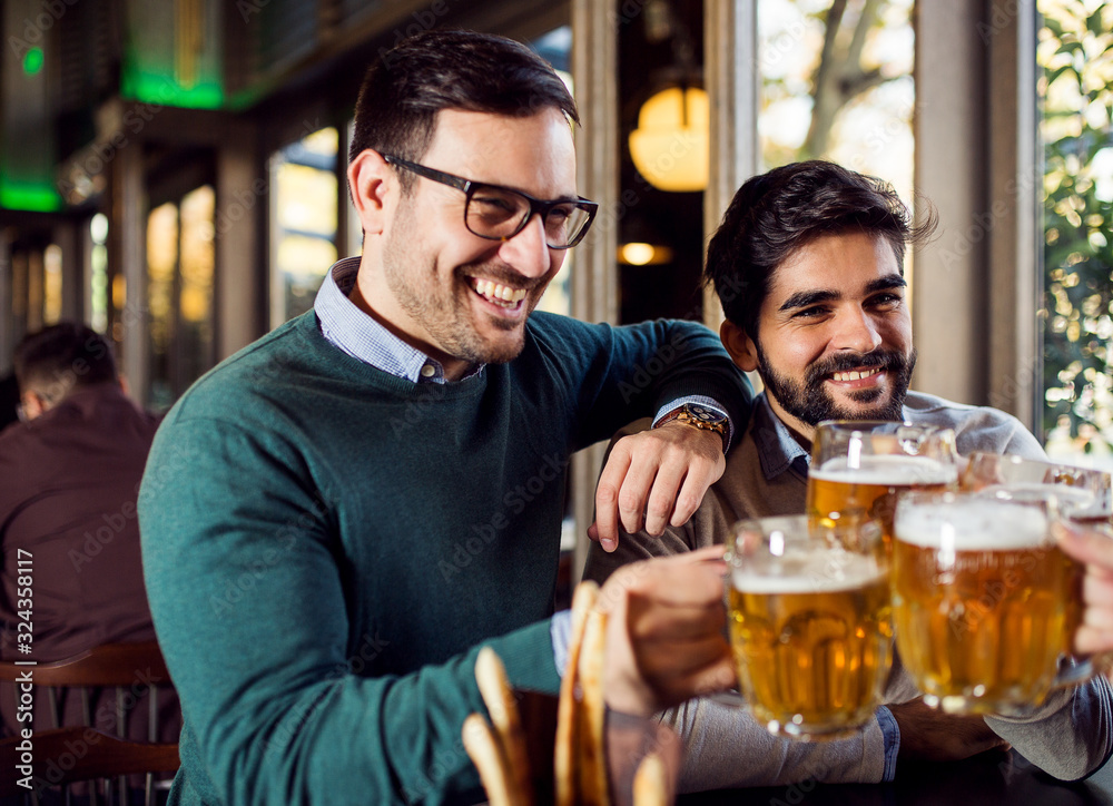 Smiling friends toasting with beer in pub