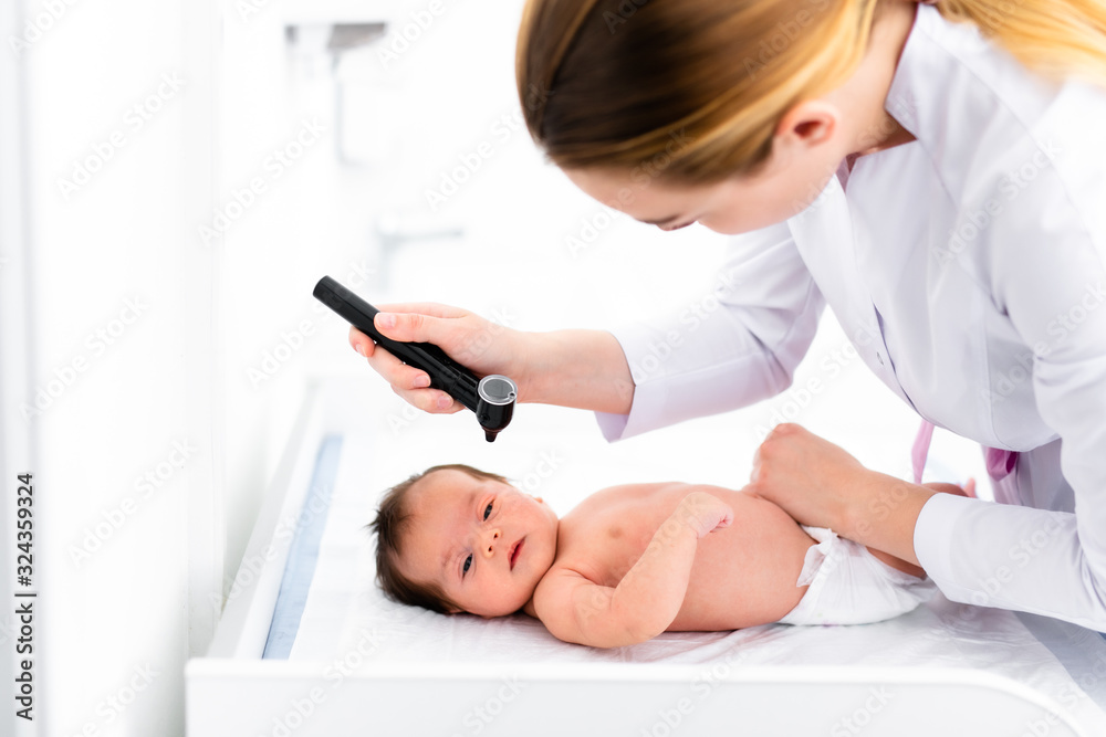 Pediatrician examines 2 week old baby's ear in new pediatric clinic