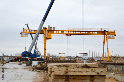 A large modern construction site in the construction of buildings and houses with appliances and many large high tower and stationary industrial powerful cranes and building materials