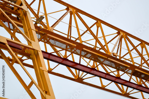 High heavy yellow metal iron load-bearing construction stationary industrial powerful gantry crane of bridge type on supports for lifting cargo on a modern construction site of buildings and houses