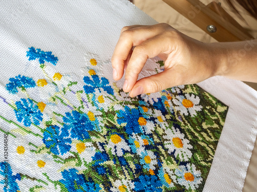 embroidery process close-up. female hand embroiders a floral ornament with a needle. hobby and needlework concept