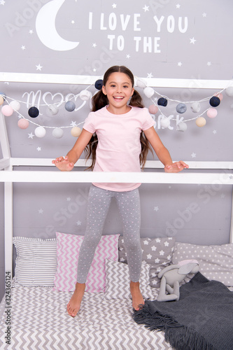 Child in pajamas. Happy morning. Coziest place on the planet is my bedroom. Cute cozy bedroom for small girl. Girl having fun bedroom interior. Childhood concept. Bedroom place relax and enjoy rest photo