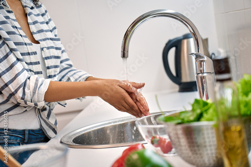 Young adult woman washing hands on kitchen