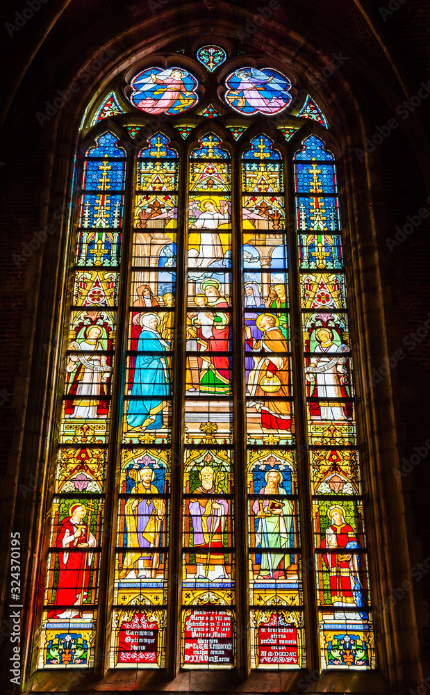 Religious scenes on gothic stained glass window inside St Michael's church inGhent, Belgium