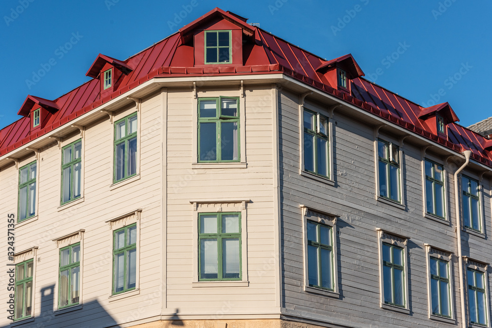 Facade of a beige wooden apartment building with red roof.