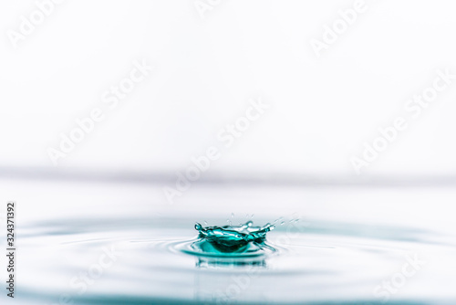 Green colored water drop splashing in clear water.