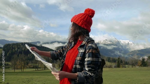 Young lady traveler with a backpack and a map on the background of the Alps. Active leisure, lifestyle sports, hiking in the mountains. Travelling in Europe.
