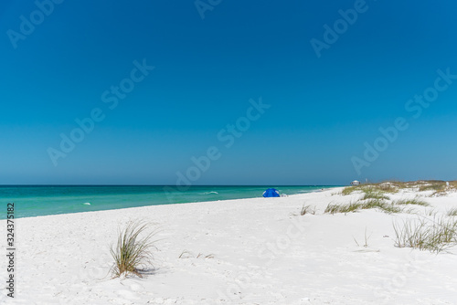 Fototapeta Naklejka Na Ścianę i Meble -  Blue umbrella on a beautiful white sand beach, Shell Island, Panama City Beach, Florida	