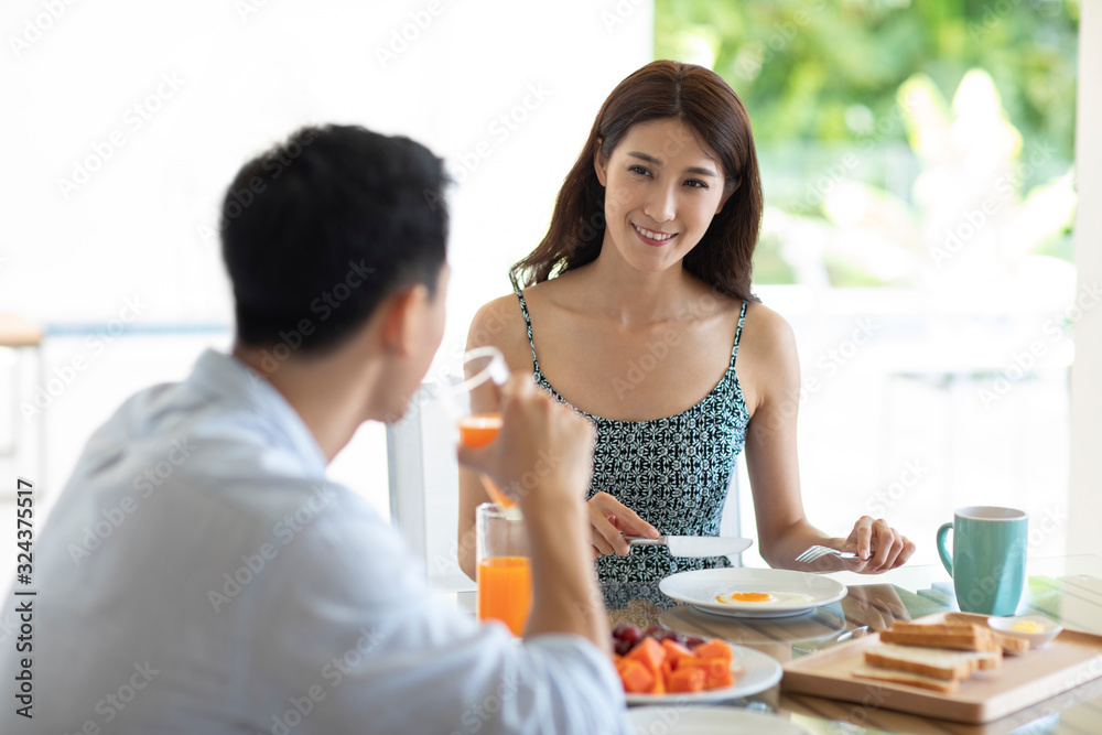 Happy young Chinese couple having breakfast in hotel room Happy young Chinese couple having breakfast in hotel room