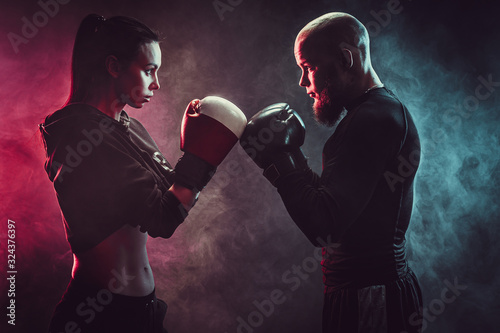 Canvas Print Woman exercising with trainer at boxing and self defense lesson, studio, smoke on background
