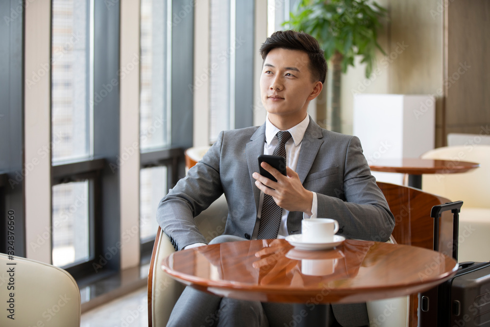 Confident Chinese businessman drinking coffee in airport lounge Confident Chinese businessman drinking coffee in airport lounge