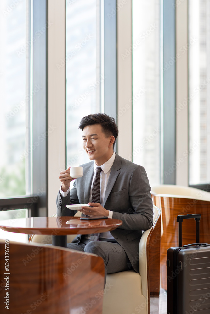 Confident Chinese businessman drinking coffee in airport lounge Confident Chinese businessman drinking coffee in airport lounge