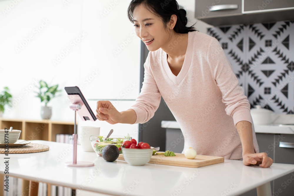 Happy young Chinese woman cooking in kitchen Happy young Chinese woman cooking in kitchen