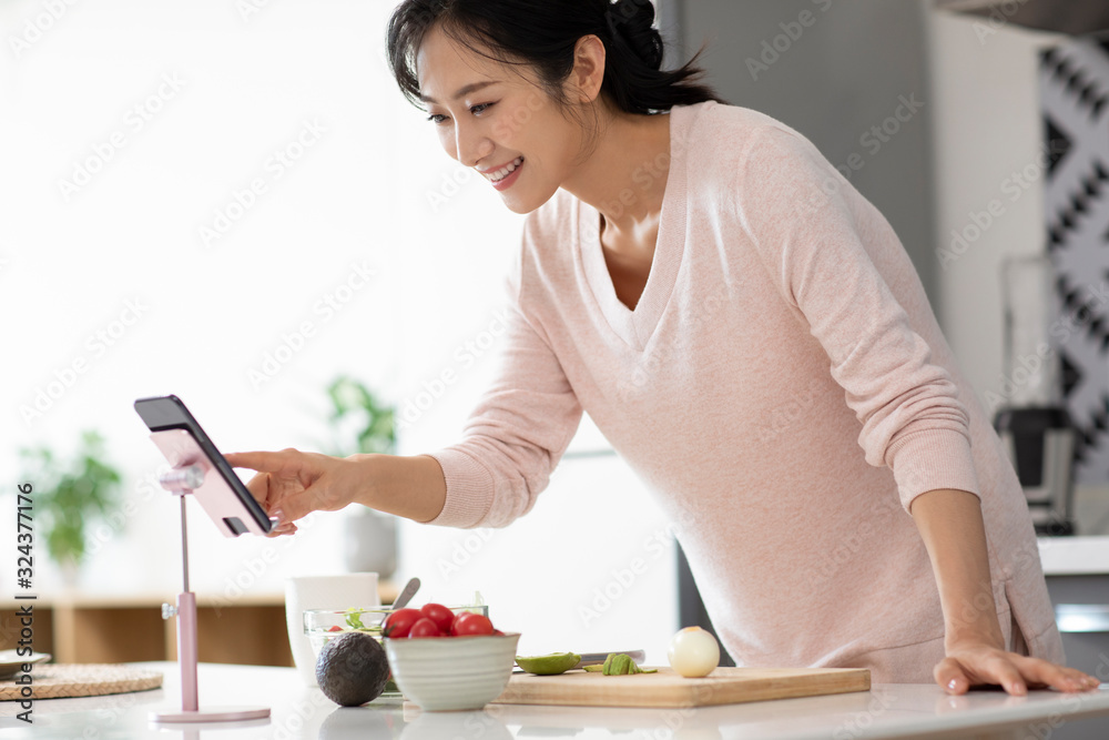 Happy young Chinese woman cooking in kitchen Happy young Chinese woman cooking in kitchen