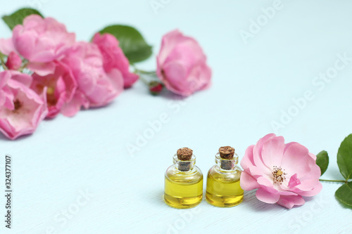 Rosehip cosmetic oil in mini bottles and pink rosehip flowers. Spa treatments for relaxation.