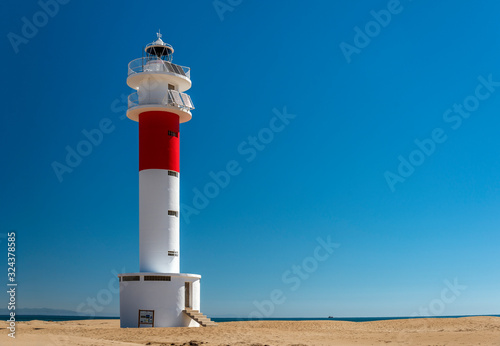 View of the El Fangar lighthouse, at the mouth or delta of the Ebro river, in Tarragona (Spain), during a sunny summer day.
