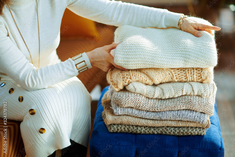 Closeup on elegant woman folding sweaters for storage