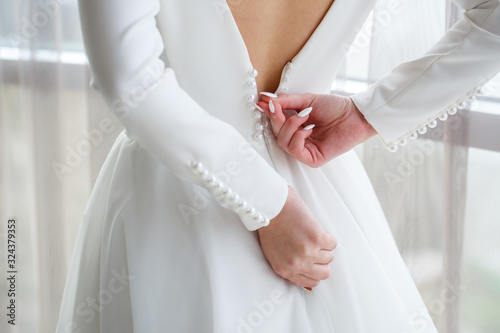 Bride zips zipper on her wedding white dress